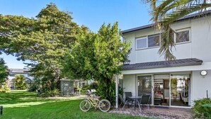 Une maison moderne à deux étages, dotée d’un patio couvert, d’un vélo et d’une pelouse bien entretenue.
