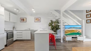 Une cuisine moderne avec des meubles blancs, un îlot central et des tabourets de bar rouges.