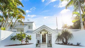 A modern house with a white exterior, a gated entrance, and a well-maintained lawn. - Island living in the heart of Noosa (Noosa Heads)
