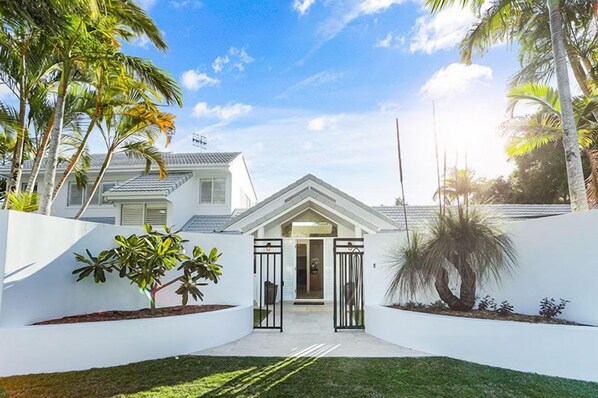 Una casa moderna con fachada blanca, un portón y un césped bien cuidado.