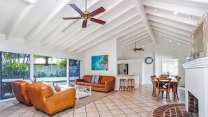 A spacious living area with a high ceiling, a fireplace, and a dining area with wooden furniture. - Island living in the heart of Noosa (Noosa Heads)