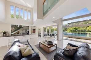 Relax in a spacious living area with expansive views of the lush landscape and pool.