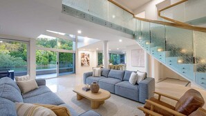 A spacious living area with a modern staircase, large windows, and a comfortable seating arrangement. - 31 Witta Circle, Noosa Heads (Noosa Heads)