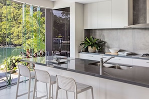 Enjoy cooking in this well-equipped kitchen with a large island, gas stove, and dining area overlooking a lush garden.