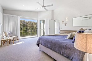 Relax in this serene bedroom with a large bed, ceiling fan, and stunning lake views through the sliding glass door.