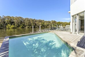 Relax by the serene pool surrounded by lush greenery and trees.