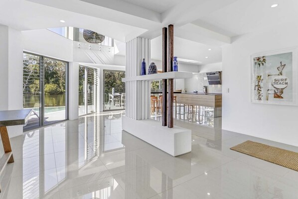 Relax in a spacious, open-plan living area with a high ceiling and sliding glass door leading to a poolside patio.