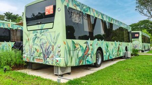 Een groene bus met bloemenmotieven en een bord met de tekst 'Bedankt voor het voorrang verlenen'.