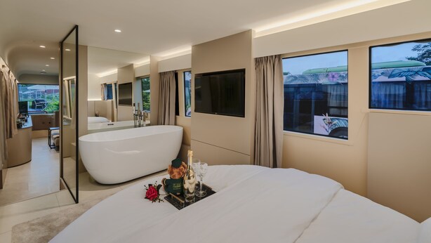 Een moderne hotelkamer met een groot bed, een badkuip en een grote spiegel.