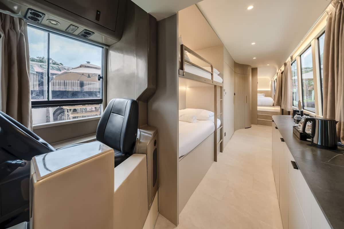 A modern train compartment with a dining area, a sleeping berth, and a window with a view of buildings.