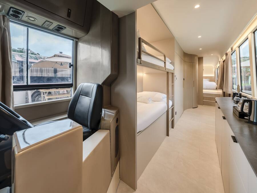 A modern train compartment with a dining area, a sleeping berth, and a window with a view of buildings.