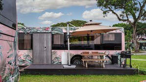 Een stacaravan met een terras, een tafel en een barbecue.