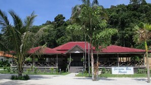 A resort with a red-roofed building, palm trees, and a sign reading "Saracen Bay Resort". - Saracen Bay Resort (Koh Rong Sanloem)