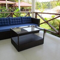 Un sofá azul y una mesa con cubierta de vidrio en un patio al aire libre.