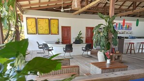 A cozy outdoor seating area with wicker furniture, a central table, and potted plants. - Saracen Bay Resort (Koh Rong Sanloem)
