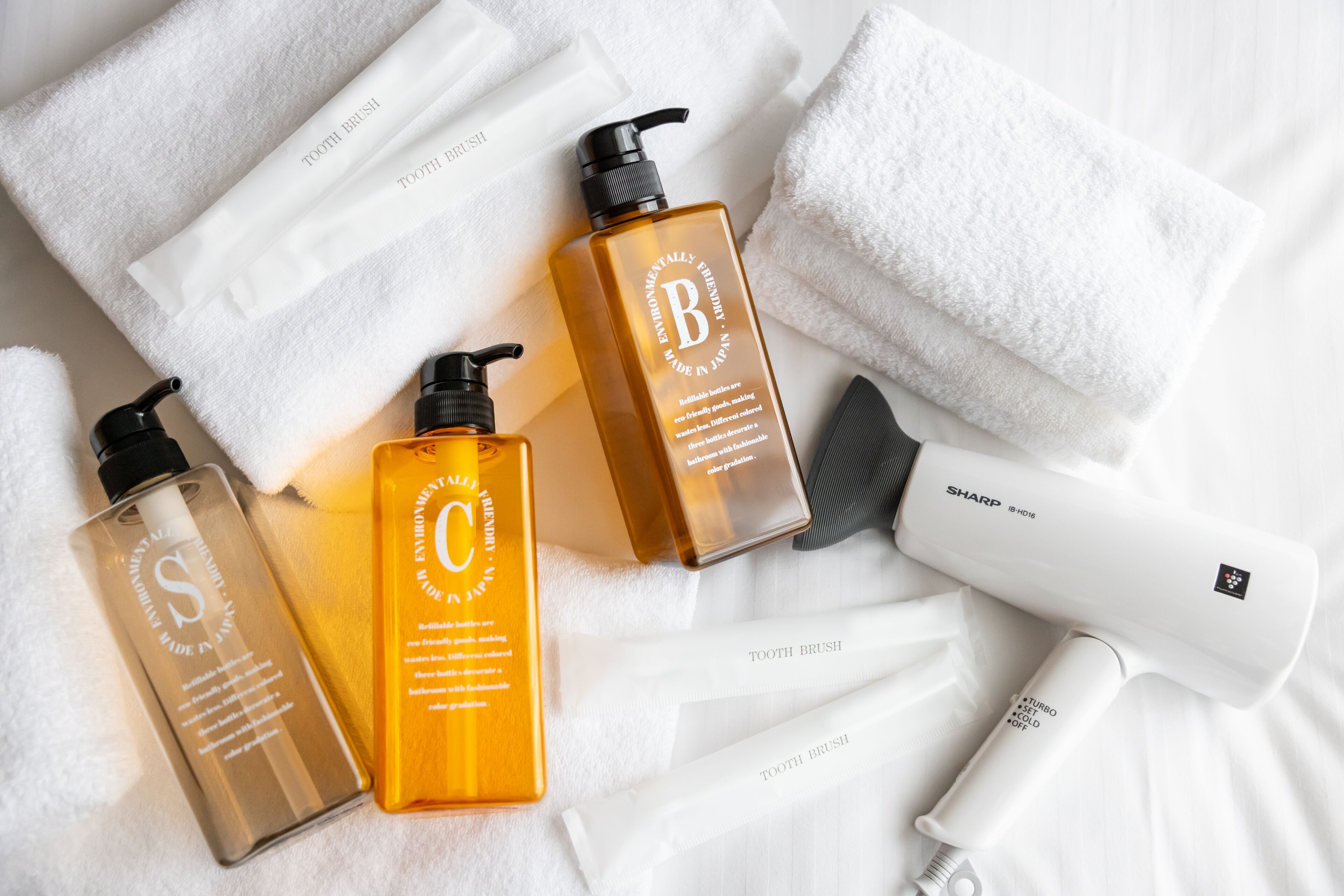 A bathroom with a white towel, a hairdryer, and two bottles of hair care products.