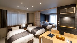 A hotel room with two beds, a desk, and a view of the adjacent room.