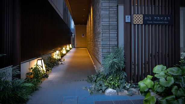 A corridor with a wooden fence, a signboard, and potted plants.