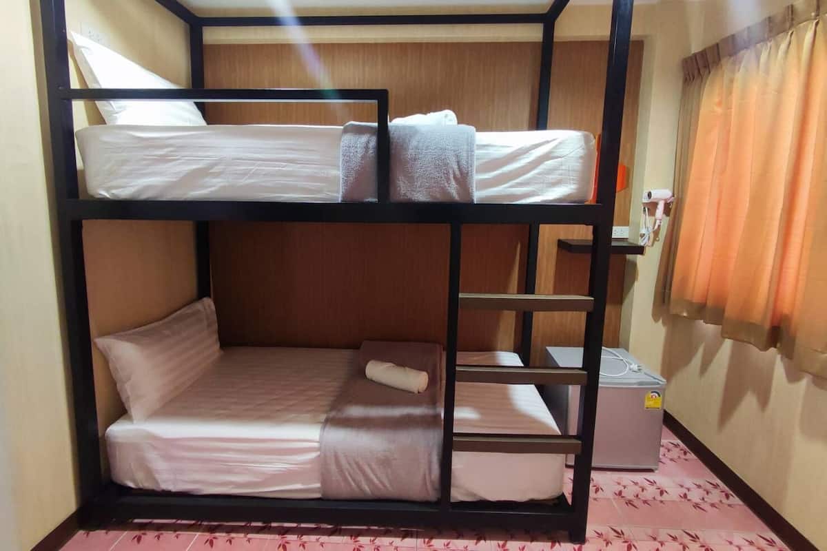 A bunk bed room with a small desk and a hairdryer on the wall.