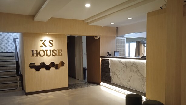 A hotel reception area with a wooden reception desk, a marble counter, and a sign that reads "KS HOUSE". - KS HOUSE (Bangkok)