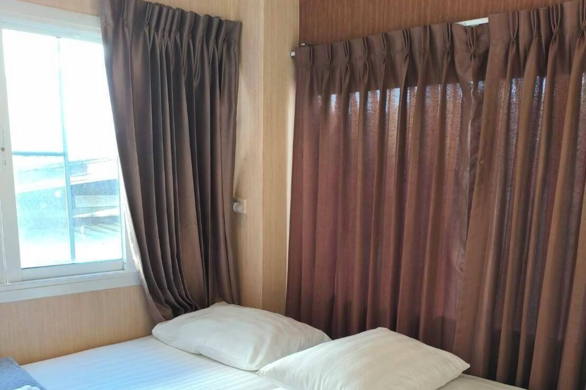 A room with two beds, a window, and curtains.