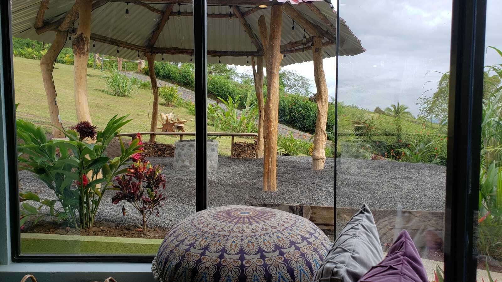 Quarto com uma grande janela que se abre para um jardim com um coreto, almofada estampada e vista para o exterior.