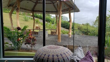 Quarto com uma grande janela que se abre para um jardim com um coreto, almofada estampada e vista para o exterior.