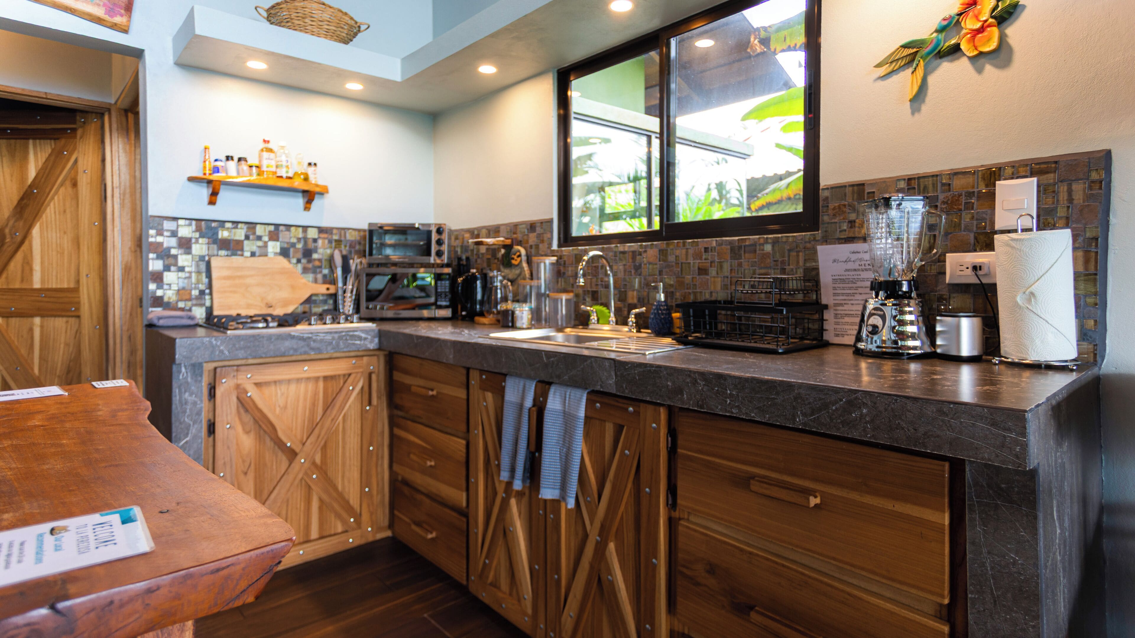 A modern kitchen with wooden cabinets, a built-in microwave, and a large window.