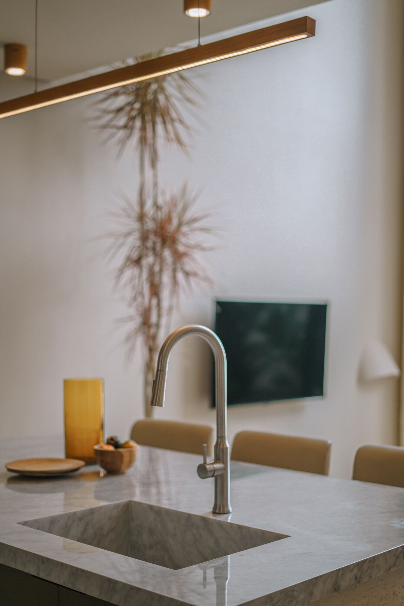 A modern kitchen with a stainless steel faucet, a marble countertop, and a dining area with a table and chairs.