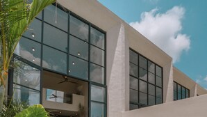 Een modern gebouw met grote ramen en een zwembadgedeelte met ligbedden en een jacuzzi.