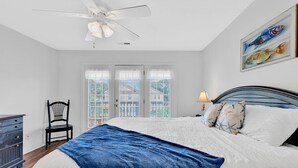 Ein Schlafzimmer mit Bett, Stuhl, Schreibtisch und Deckenventilator.