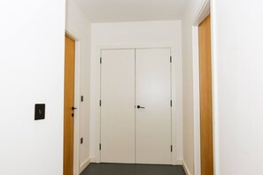 Un pasillo con una puerta doble, un interruptor de luz y detalles de madera en las paredes.