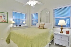A bedroom with a bed, two bedside tables, a ceiling fan, and a window with blinds. - Entire Compound on Gated Bayfront Property (Islamorada)
