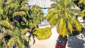 Ein tropisches Resort mit Pool, umgeben von Palmen und einem roten Auto davor geparkt.