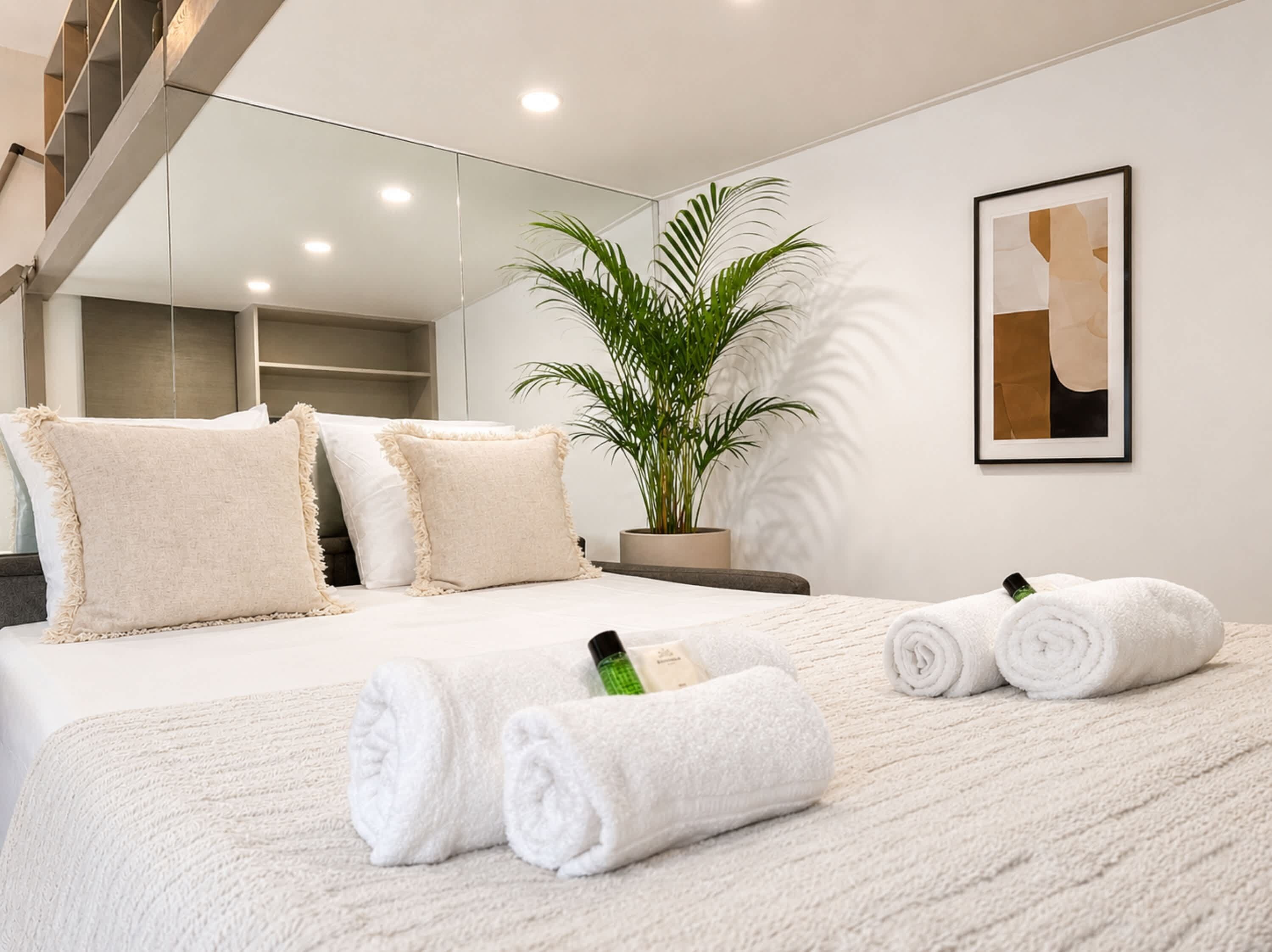 Moderni hotellihuone, jossa on suuri sänky, ruukussa oleva kasvi ja seinällä oleva taideteos.