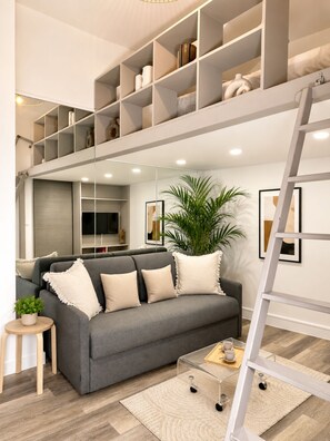 A modern living room with a grey sofa, a coffee table, a potted plant, and a white ladder. - Stylish studio near the Tuileries Gardens (Paris)