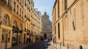 Une vue de rue avec des bâtiments, une église surmontée d’un dôme et un clocher.