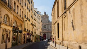 Une vue de rue avec des bâtiments, une église surmontée d’un dôme et un clocher.