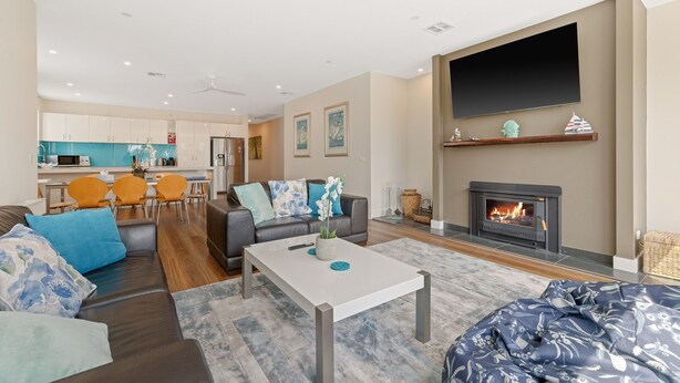 Una sala de estar moderna con chimenea, un televisor de pantalla plana y un comedor con sillas anaranjadas.