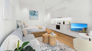 Una sala de estar moderna y minimalista con un sofá, una mesa de centro y un televisor de pantalla plana.