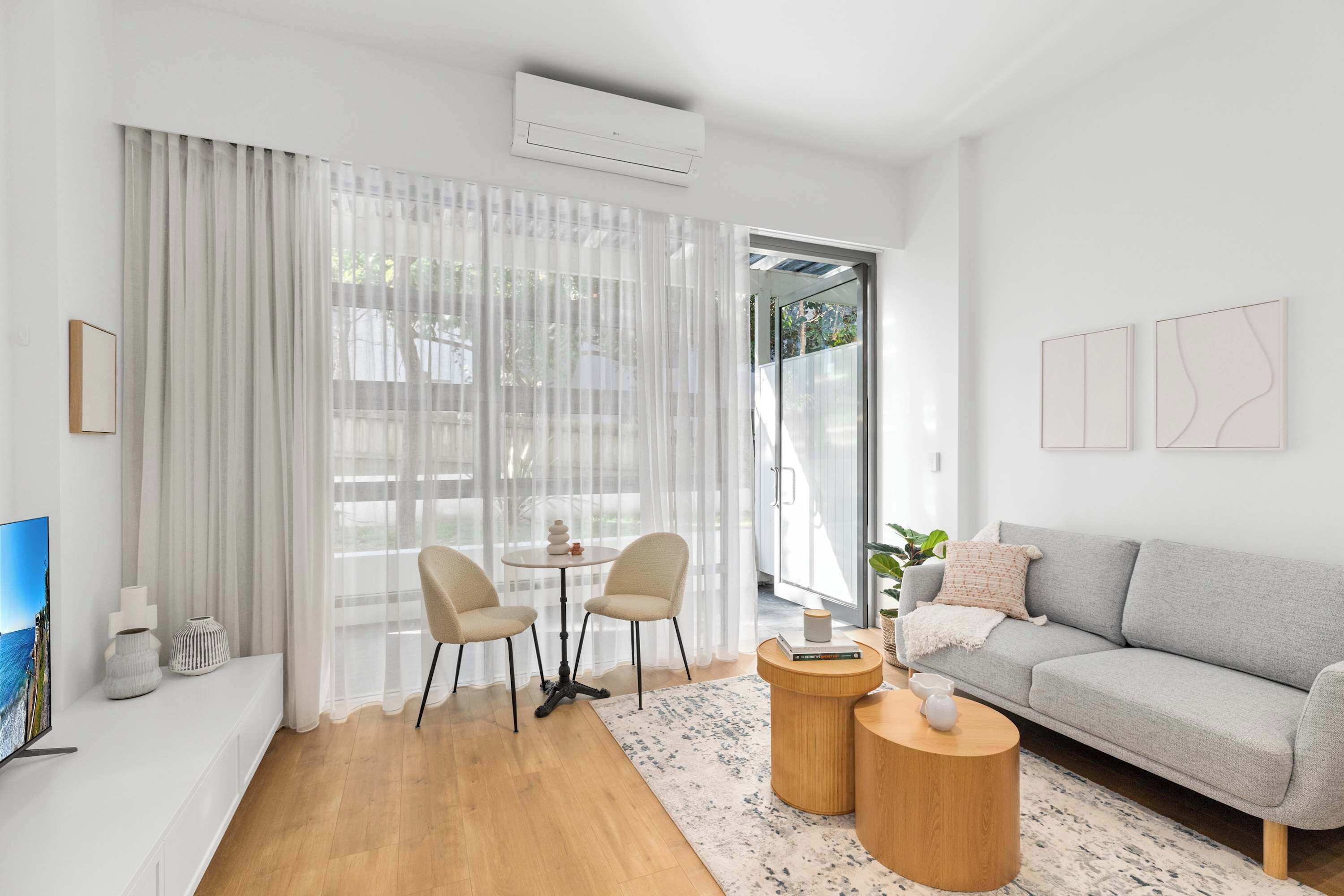 Un salon moderne comprenant un canapé, deux fauteuils, une table basse et un téléviseur.