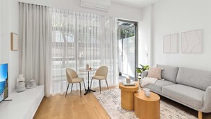 Una sala de estar moderna con un sofá, dos sillones, una mesa de centro y un televisor.