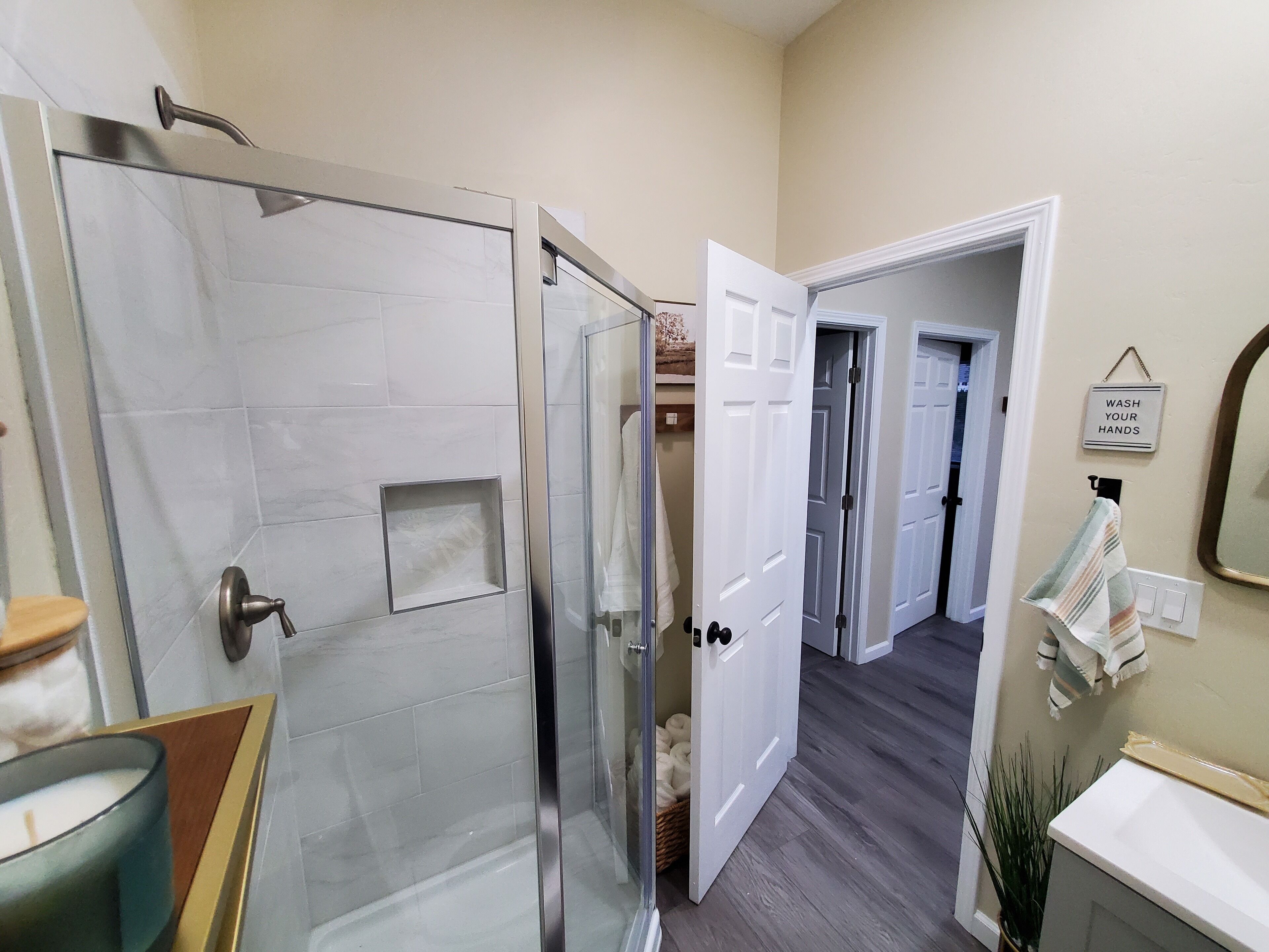 A modern bathroom with a glass shower enclosure, a sink, and a towel rack.