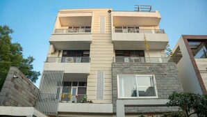 Un edificio residencial de varios pisos con balcones, ventanas amplias y fachada de piedra.