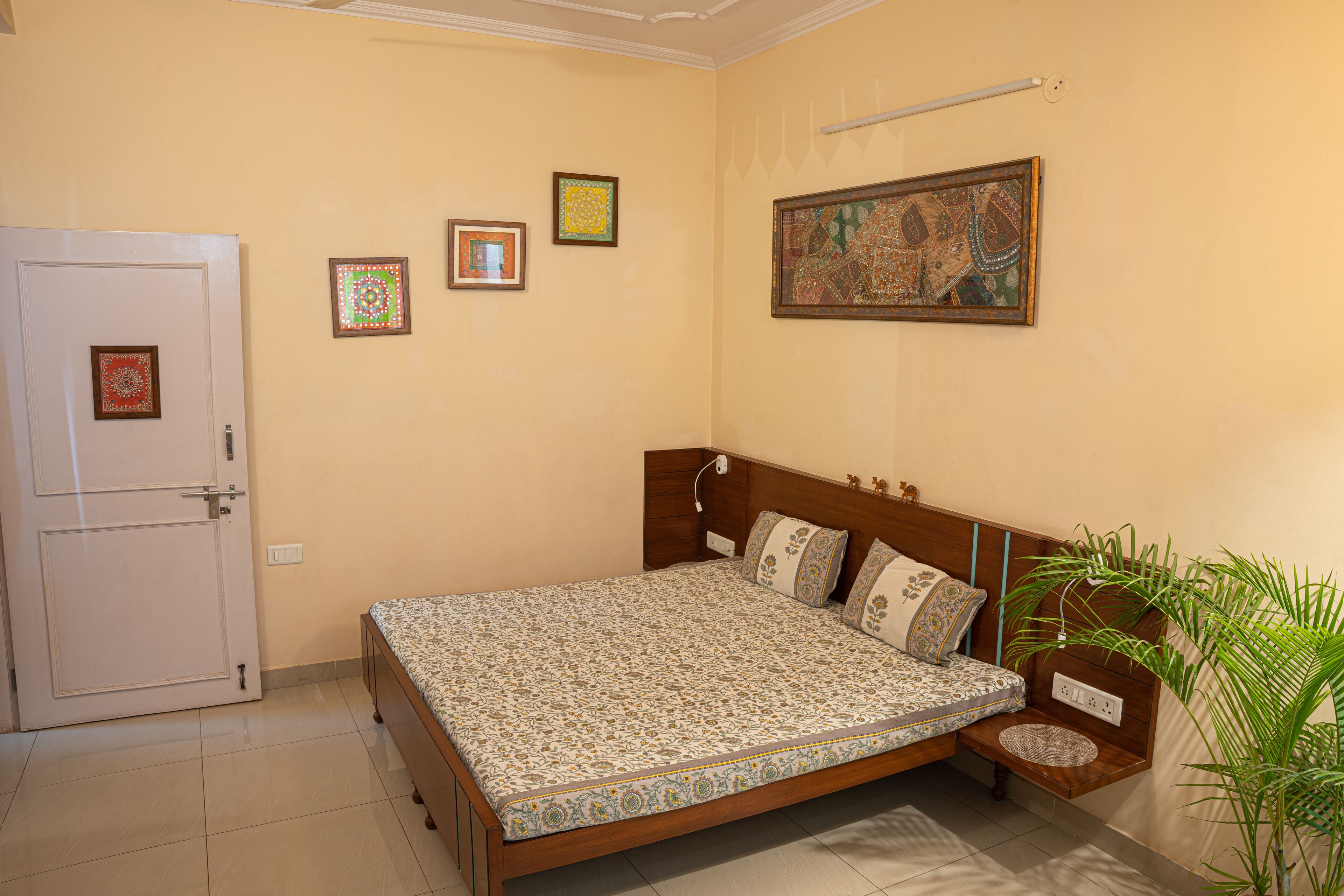A bedroom with a bed, a door, and a wall with three framed pictures.