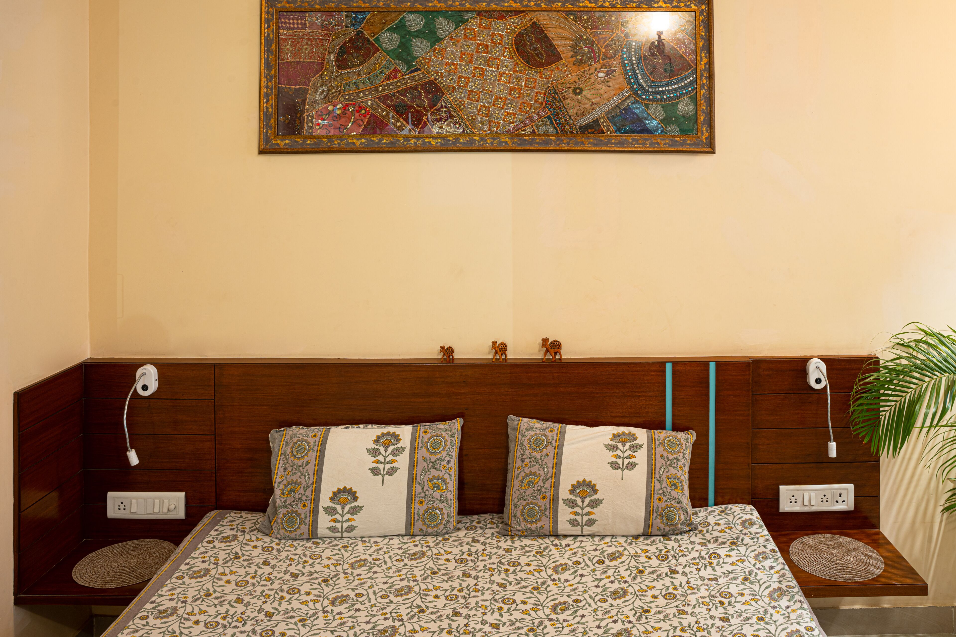 A neatly made bed with patterned bedding, a wall-mounted artwork, and a wooden headboard.