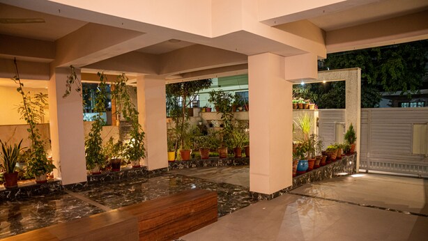 Un espacio interior amplio con piso de mármol, bancos de madera y plantas en macetas.
