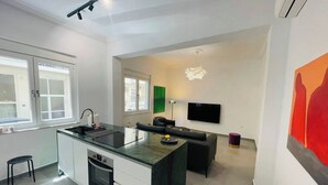 Une cuisine moderne dotée d’un îlot central, d’un coin repas avec un canapé et d’un téléviseur à écran plat fixé au mur.