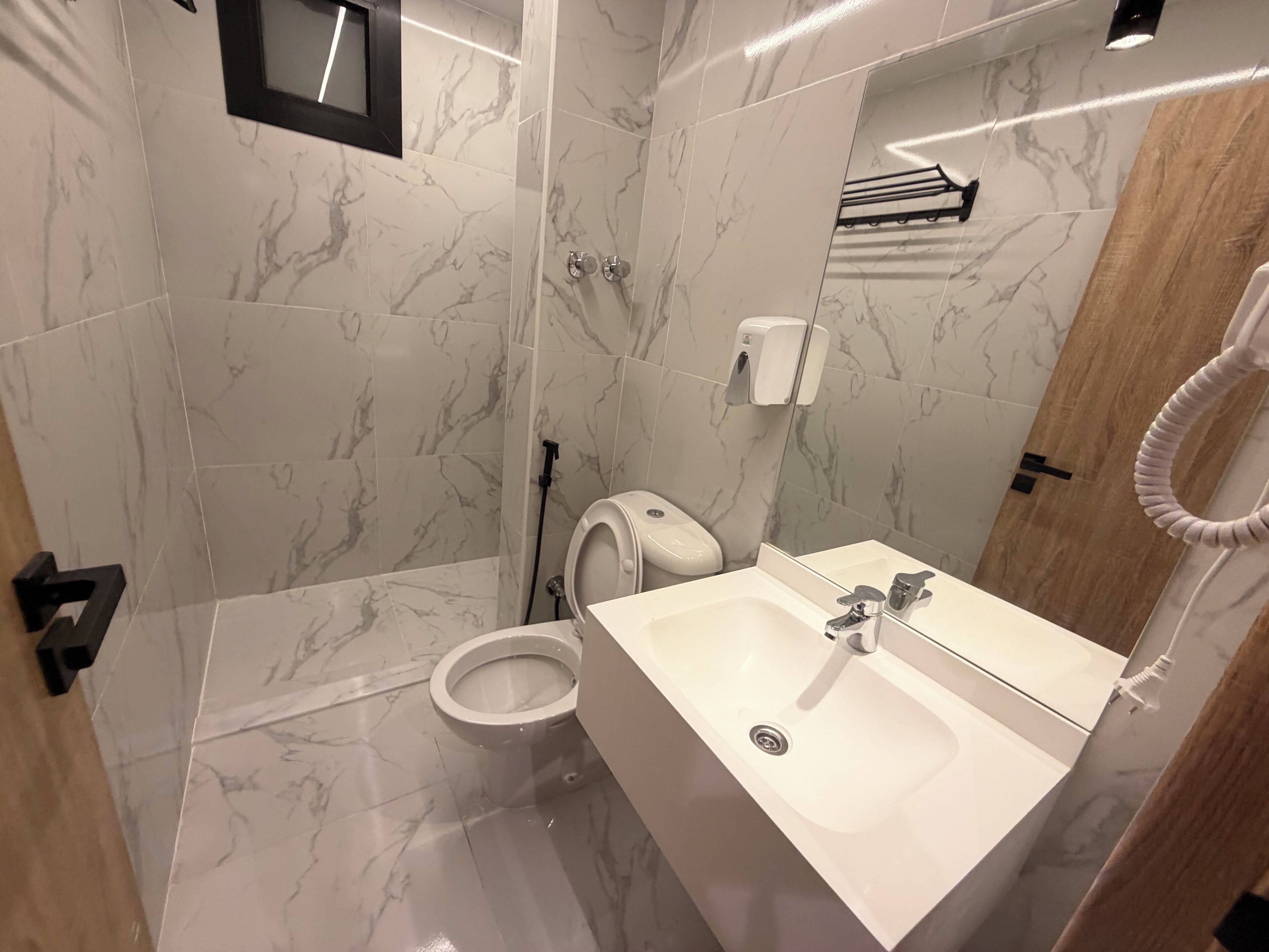 A bathroom with a toilet, sink, mirror, and shower area.