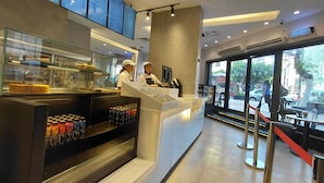 A modern café interior with a counter, menu boards, and a view of the street outside. - Atlas Hotels (Cairo)